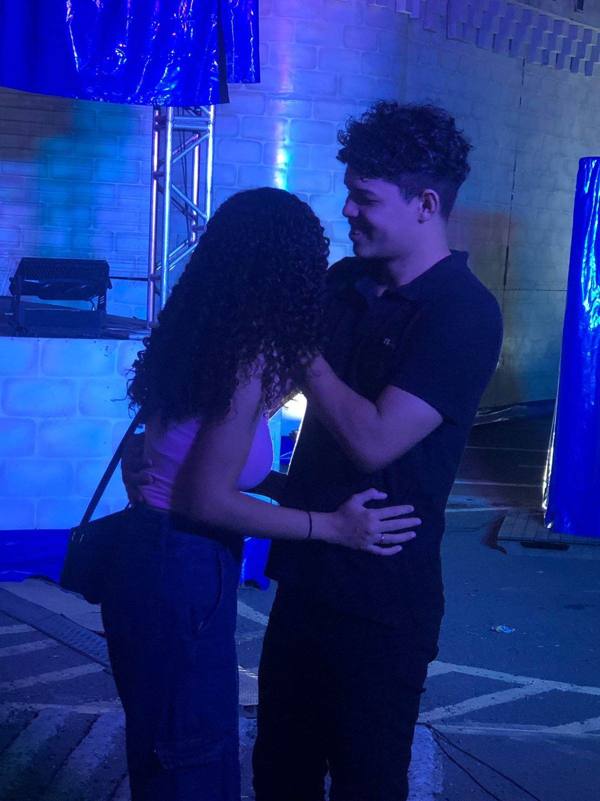 Caio e Carla juntos sob luzes azuis em 2024